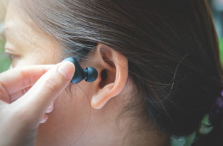 一个黑发的女人正把耳塞塞进耳朵里。