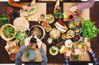 人们聚集在一张摆满素食和植物性食物的餐桌前用餐。