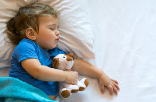 小男孩抱着毛绒玩具睡觉。
