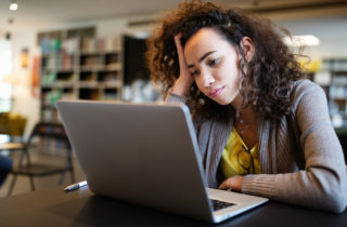 一位患有多动症的妇女看着她的笔记本电脑，脸上带着沉思的表情。
